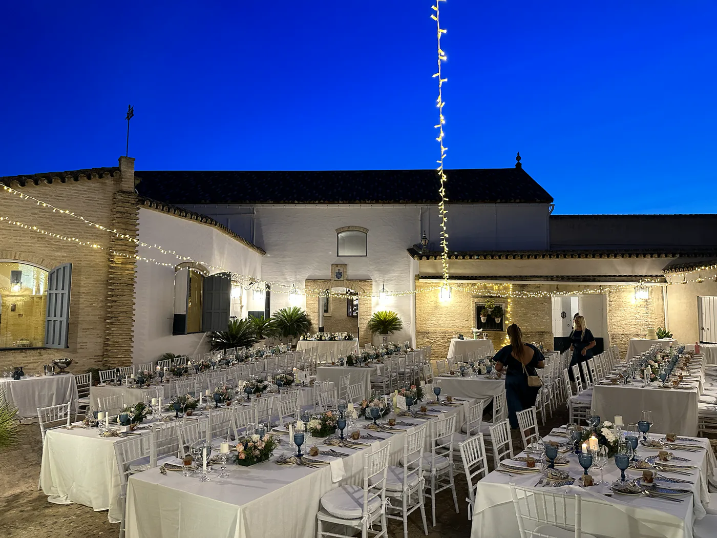 Patio iluminado al anochecer y preparado para una cena de boda